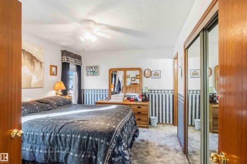 Carpeted bedroom with a textured ceiling, a ceiling fan, and a closet - 17619 94 Ave, Edmonton, AB - Indoor Photo Showing Bedroom