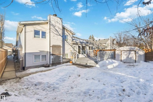 Snow covered rear of property featuring a storage unit, a fenced backyard, a deck, and a chimney - 17619 94 Ave, Edmonton, AB - Outdoor