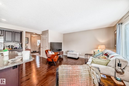 Living area featuring dark wood-style floors and a textured ceiling - 9645 Simpson Place, Edmonton, AB 