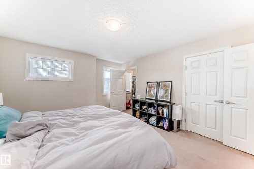 Bedroom with a spacious closet, carpet floors, and a textured ceiling - 9645 Simpson Place, Edmonton, AB 