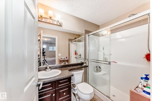 Full bathroom featuring vanity, a stall shower, and a textured ceiling - 9645 Simpson Place, Edmonton, AB 