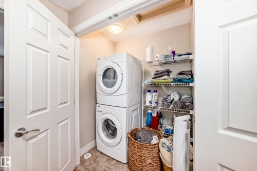Laundry area with stacked washer and dryer and a textured ceiling - 9645 Simpson Place, Edmonton, AB 