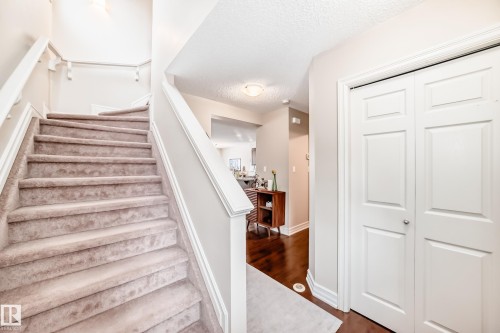 Staircase with a textured ceiling and wood finished floors - 9645 Simpson Place, Edmonton, AB 