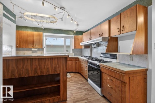 Kitchen with gas range, tasteful backsplash, wood finish cabinetry, and tile counters - Edmonton, AB - Indoor Photo Showing Kitchen