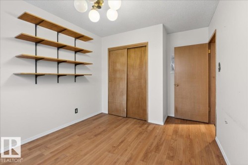 Unfurnished bedroom with a textured ceiling, light wood-style floors, a closet, and suspended lighting - Edmonton, AB - Indoor Photo Showing Other Room