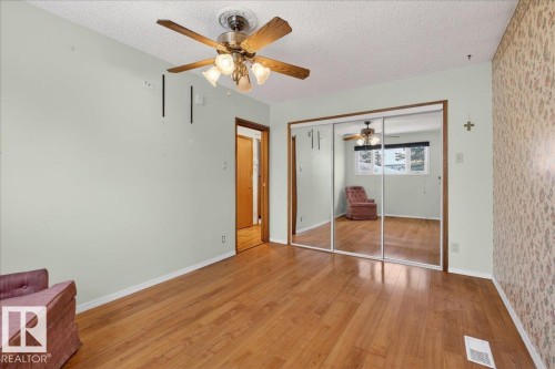 Unfurnished bedroom featuring a textured ceiling, light wood finished floors, ceiling fan, and a closet - Edmonton, AB - Indoor Photo Showing Other Room