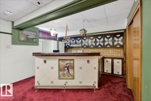 Indoor bar featuring a drop ceiling, dark carpet, white refrigerator with ice dispenser, and pendant lighting - Edmonton, AB -  Photo Showing Other Room