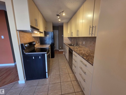 Kitchen with range with electric cooktop, light tile patterned floors, a textured ceiling, backsplash, and dishwashing machine - 701 10155 114 Street, Edmonton, AB - Indoor Photo Showing Kitchen