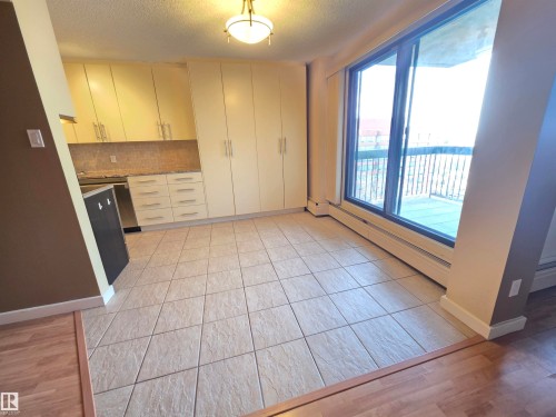 Kitchen with a textured ceiling, light wood-style flooring, a baseboard radiator, and decorative backsplash - 701 10155 114 Street, Edmonton, AB - Indoor Photo Showing Other Room