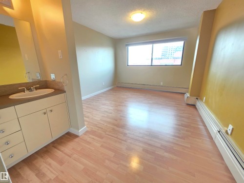 Bathroom with vanity, a baseboard heating unit, a textured ceiling, and light wood-style floors - 701 10155 114 Street, Edmonton, AB - Indoor