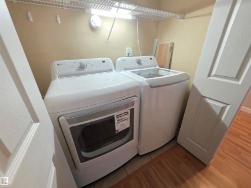 Laundry area featuring light wood finished floors and washing machine and dryer - 701 10155 114 Street, Edmonton, AB - Indoor Photo Showing Laundry Room