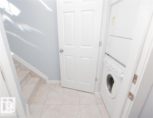 Laundry area with stacked washing machine and dryer and light tile patterned floors - 17208 106 Street, Edmonton, AB - Indoor Photo Showing Laundry Room
