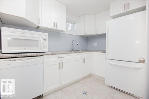 Kitchen featuring white appliances, white cabinets, light tile patterned floors, and light stone counters - 17208 106 Street, Edmonton, AB - Indoor Photo Showing Kitchen