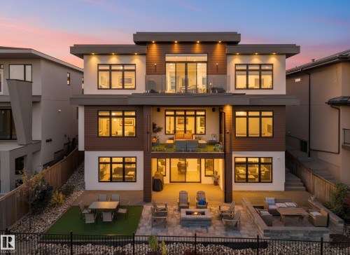Back of house at dusk with a patio, an outdoor fire pit, stucco siding, a fenced backyard, and outdoor lounge area - 4809 Woolsey Lane, Edmonton, AB - Outdoor