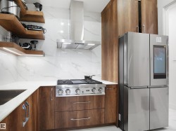 Kitchen with stainless steel appliances, island exhaust hood, wood finish cabinetry, and backsplash - 
