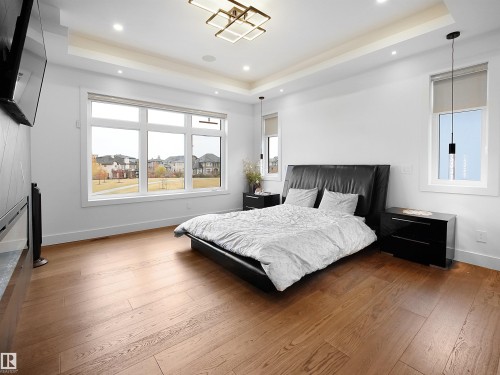 Bedroom with hardwood / wood-style floors, a tray ceiling, and recessed lighting - 4809 Woolsey Lane, Edmonton, AB - Indoor Photo Showing Bedroom