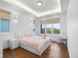 Bedroom featuring wood-type flooring, a tray ceiling, and recessed lighting - 
