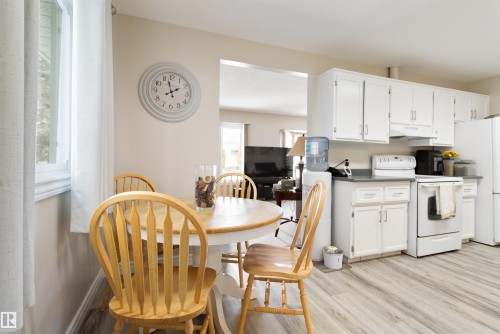 Kitchen with white range with electric cooktop, light wood-style flooring, dark countertops, and white cabinetry - 4423 18 Avenue, Edmonton, AB - Indoor