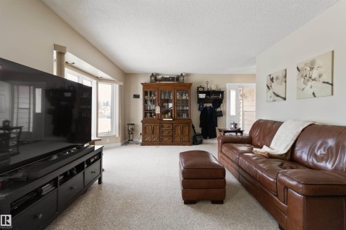 Living area with a textured ceiling, plenty of natural light, and light colored carpet - 4423 18 Avenue, Edmonton, AB - Indoor Photo Showing Living Room