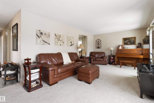 Living area with light colored carpet, a wood stove, and a textured ceiling - 4423 18 Avenue, Edmonton, AB - Indoor Photo Showing Living Room