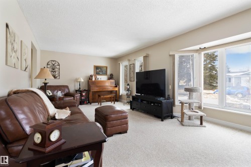 Carpeted living room featuring a textured ceiling and baseboards - 4423 18 Avenue, Edmonton, AB - Indoor Photo Showing Living Room
