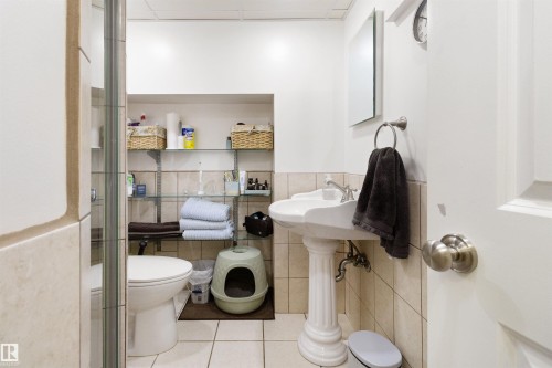 Full bath with a paneled ceiling, tile patterned floors, a shower with shower door, tile walls, and wainscoting - 4423 18 Avenue, Edmonton, AB - Indoor Photo Showing Bathroom