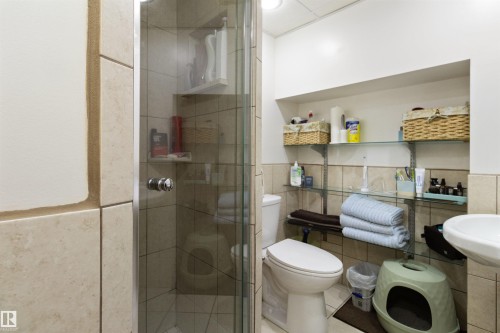 Full bath featuring tile walls, a shower stall, tile patterned floors, and wainscoting - 4423 18 Avenue, Edmonton, AB - Indoor Photo Showing Bathroom