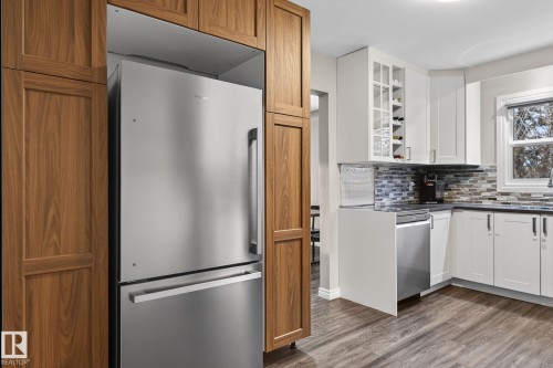 Kitchen with stainless steel appliances, light wood-style floors, tasteful backsplash, glass fronted cabinets, and white cabinetry - 5 Langley Drive, Fort Saskatchewan, AB - Indoor Photo Showing Kitchen