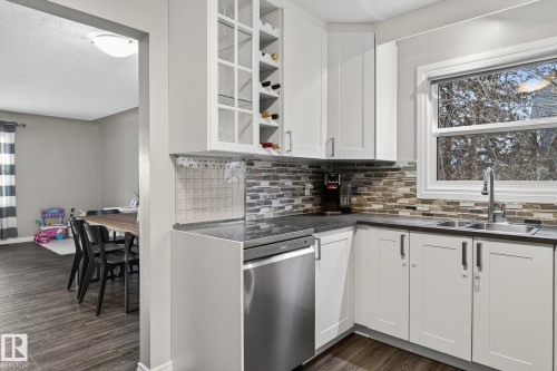 Kitchen with dishwasher, dark wood-style flooring, dark countertops, and white cabinetry - 5 Langley Drive, Fort Saskatchewan, AB - Indoor Photo Showing Kitchen With Double Sink