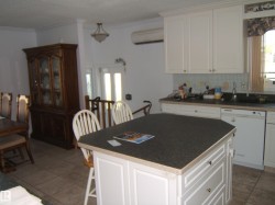 Kitchen with white dishwasher, backsplash, light tile patterned floors, crown molding, and dark countertops - 