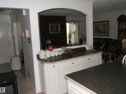 Kitchen with crown molding, dark countertops, white cabinets, light tile patterned floors, and open floor plan - 4807 54 Avenue, Two Hills, AB - Indoor