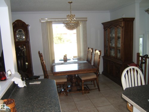 Dining room featuring crown molding, light tile patterned flooring, plenty of natural light, a textured ceiling, and a chandelier - 4807 54 Avenue, Two Hills, AB - Indoor Photo Showing Dining Room