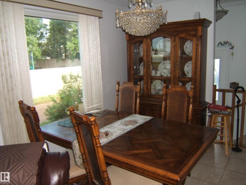 Dining area with a chandelier, healthy amount of natural light, crown molding, and light tile patterned floors - 4807 54 Avenue, Two Hills, AB - Indoor Photo Showing Dining Room