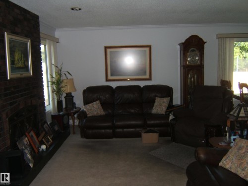 Living room featuring ornamental molding, a textured ceiling, carpet floors, and a fireplace - 4807 54 Avenue, Two Hills, AB - Indoor Photo Showing Living Room