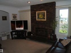 Carpeted living room featuring crown molding, a textured ceiling, and a brick fireplace - 