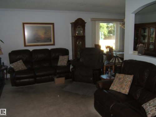 Living area featuring crown molding, carpet floors, and a chandelier - 4807 54 Avenue, Two Hills, AB - Indoor Photo Showing Living Room