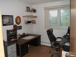 Office space featuring wood finished floors, a baseboard heating unit, and a textured ceiling - 