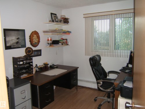 Office space featuring wood finished floors, a baseboard heating unit, and a textured ceiling - 4807 54 Avenue, Two Hills, AB - Indoor Photo Showing Office