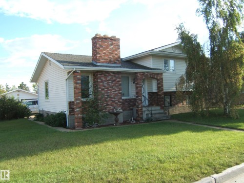 View of front of house with a chimney, a front lawn, brick siding, and a shingled roof - 4807 54 Avenue, Two Hills, AB - Outdoor