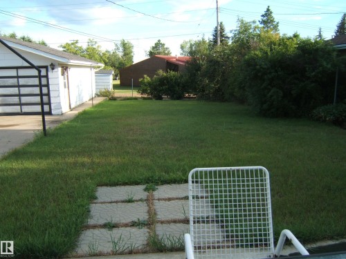View of green lawn featuring an outdoor structure and a garage - 4807 54 Avenue, Two Hills, AB - Outdoor