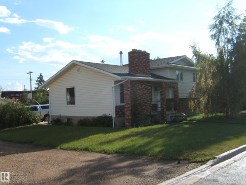 View of side of property with a yard, a chimney, and brick siding - 4807 54 Avenue, Two Hills, AB - Outdoor