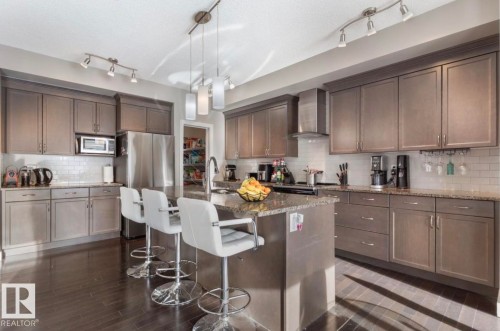 Kitchen with dark stone counters, a kitchen bar, tasteful backsplash, and dark wood finish cabinets - 21703 86 Avenue, Edmonton, AB - Indoor Photo Showing Kitchen