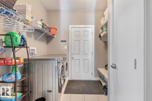 Laundry room featuring separate washer and dryer, a textured ceiling, and light tile patterned floors - 21703 86 Avenue, Edmonton, AB - Indoor Photo Showing Laundry Room