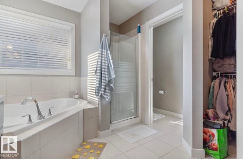 Full bath featuring a spacious closet, a stall shower, a garden tub, and light tile patterned flooring - 21703 86 Avenue, Edmonton, AB - Indoor Photo Showing Bathroom