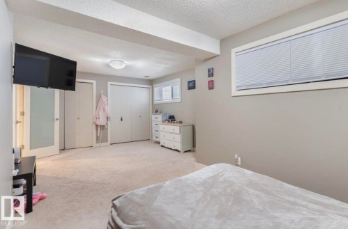 Bedroom featuring multiple closets, light colored carpet, and a textured ceiling - 21703 86 Avenue, Edmonton, AB - Indoor Photo Showing Bedroom