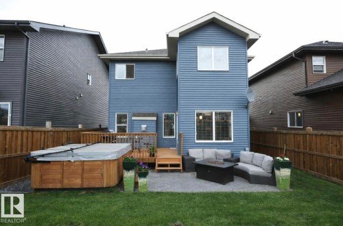 Rear view of property featuring an outdoor living space with a fire pit, a wooden deck, a fenced backyard, and a hot tub - 21703 86 Avenue, Edmonton, AB - Outdoor With Deck Patio Veranda With Exterior