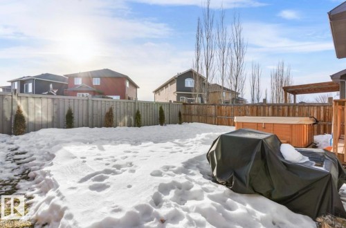 Yard covered in snow with a hot tub, a fenced backyard, and a residential view - 21703 86 Avenue, Edmonton, AB - Outdoor