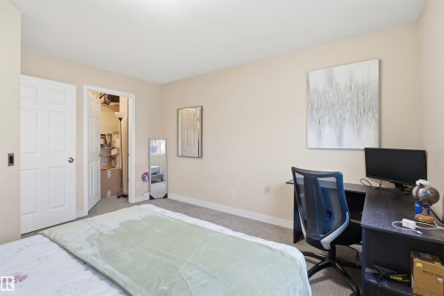 Carpeted bedroom with baseboards and a desk - 8 230 Edwards Drive, Edmonton, AB - Indoor