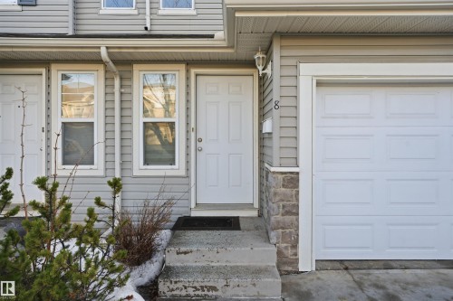 Doorway to property with a garage and stone siding - 8 230 Edwards Drive, Edmonton, AB - Outdoor With Exterior