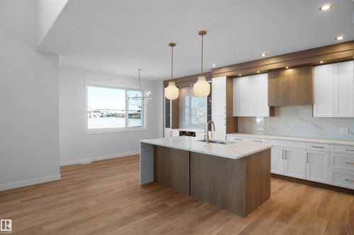 Kitchen featuring two tone cabinets, tasteful backsplash, suspended lighting, light wood-style floors, and light stone countertops - 6228 29 Avenue, Edmonton, AB - Indoor Photo Showing Kitchen With Upgraded Kitchen